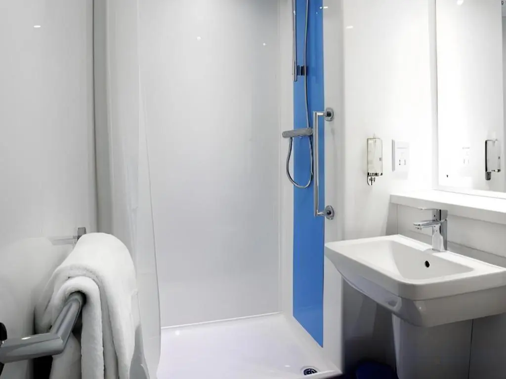 a white bathroom with a shower and a sink at Travelodge Inverness Fairways in Inshes