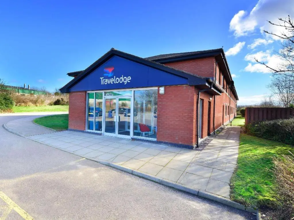 a store with a sign on the side of a building at Travelodge Aberdeen Bucksburn in Aberdeen