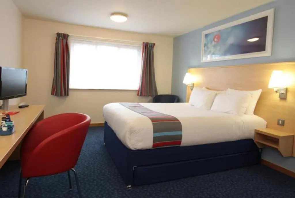 a hotel room with a bed and a desk and a television at Travelodge Aberdeen Bucksburn in Aberdeen
