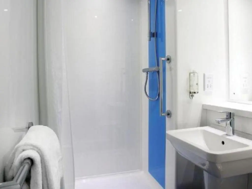 a white bathroom with a shower and a sink at Travelodge Aberdeen Bucksburn in Aberdeen