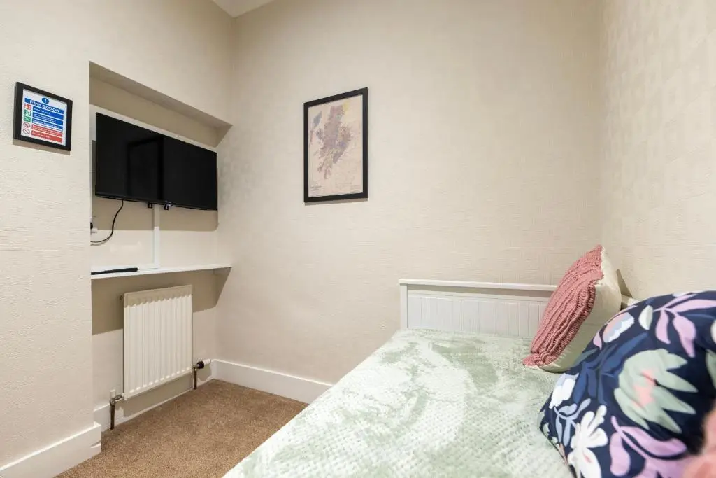 a bedroom with a bed and a flat screen tv at Century House - 4BR - Free Parking - City Centre in Inverness