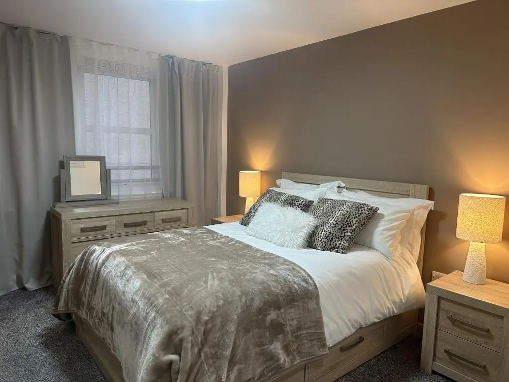 a bedroom with a bed with two lamps and a window at LaScala Apartment in Inverness