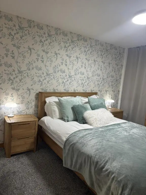 a bedroom with a bed with blue floral wallpaper at LaScala Apartment in Inverness