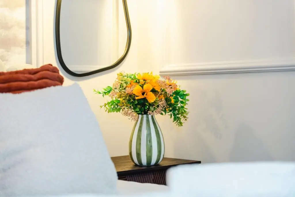 a vase with yellow flowers on a table next to a bed at Luxury New Inverness Apartment in a Prime Location in Inverness