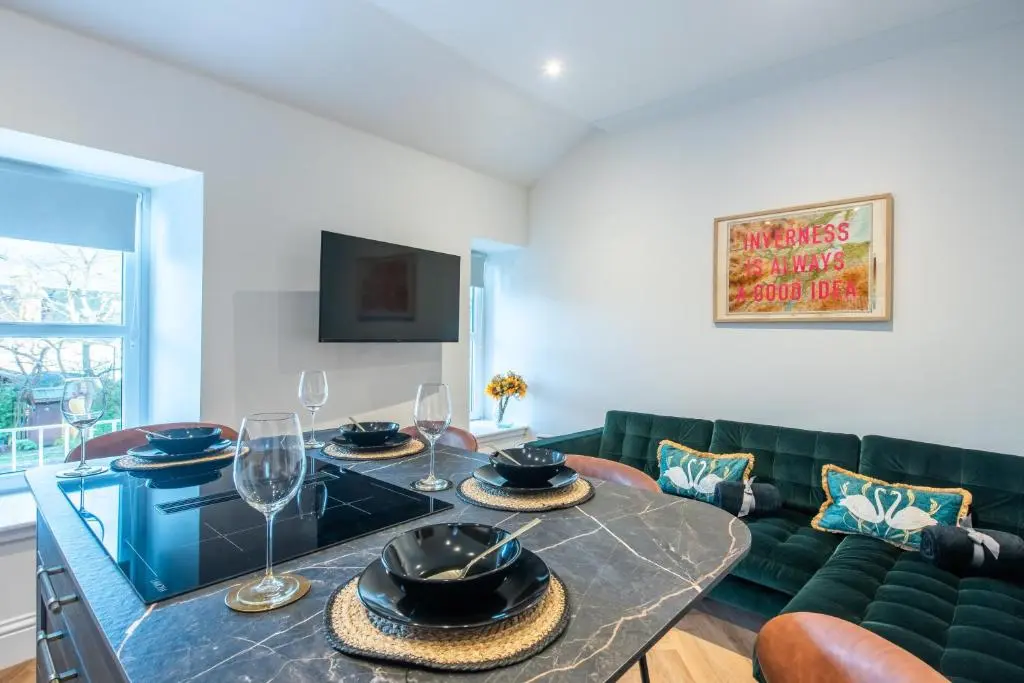 a living room with a table and a green couch at Luxury New Inverness Apartment in a Prime Location in Inverness