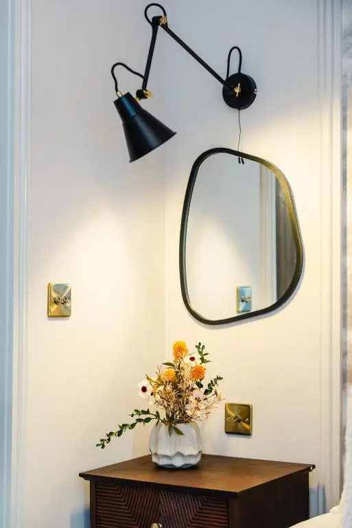 a vase of flowers on a table with a mirror at Luxury New Inverness Apartment in a Prime Location in Inverness