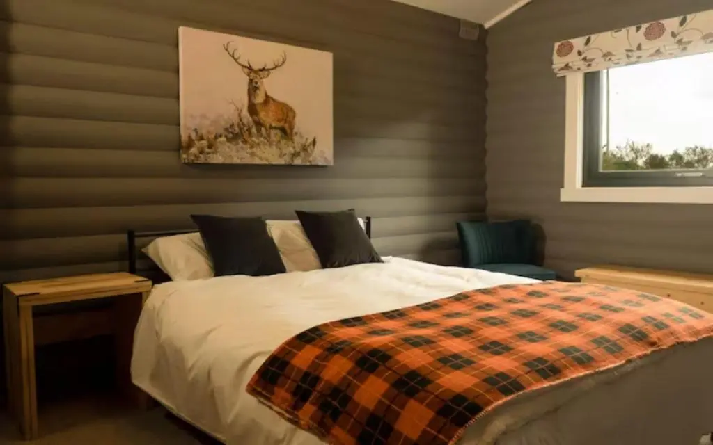 a bedroom with a bed and a deer painting on the wall at Cateran Rest in Kirkmichael