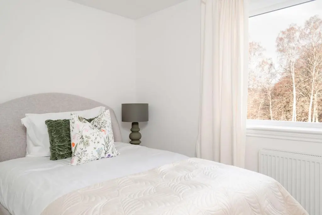a white bedroom with a bed with pillows and a window at Inshlea - Seasgair Lodges in Insh