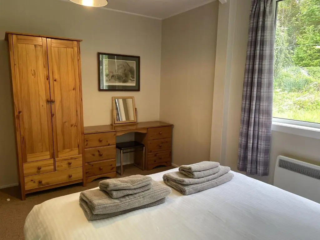a bedroom with a bed with two towels on it at Crianlarich Cottage in Fort Augustus
