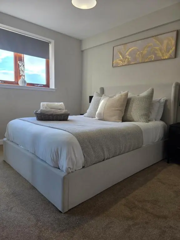 a bedroom with a large white bed with a window at Riverside View in Inverness