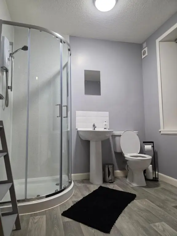 a bathroom with a shower and a toilet and a sink at 14 Harbour View in Wick