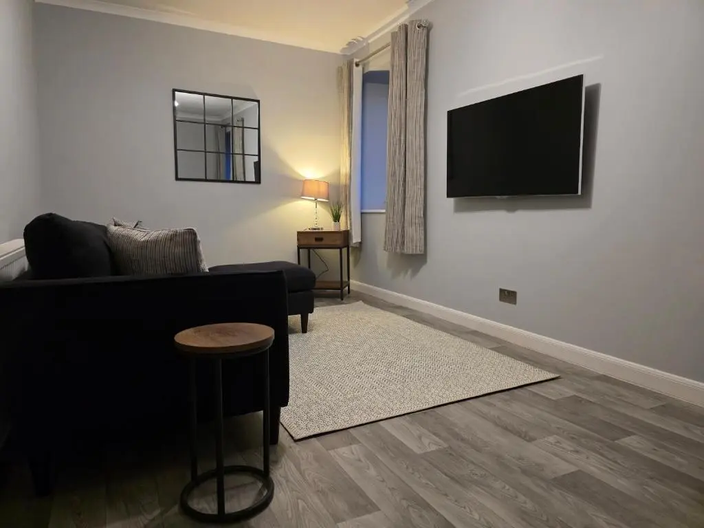 a living room with a couch and a television on a wall at 14 Harbour View in Wick