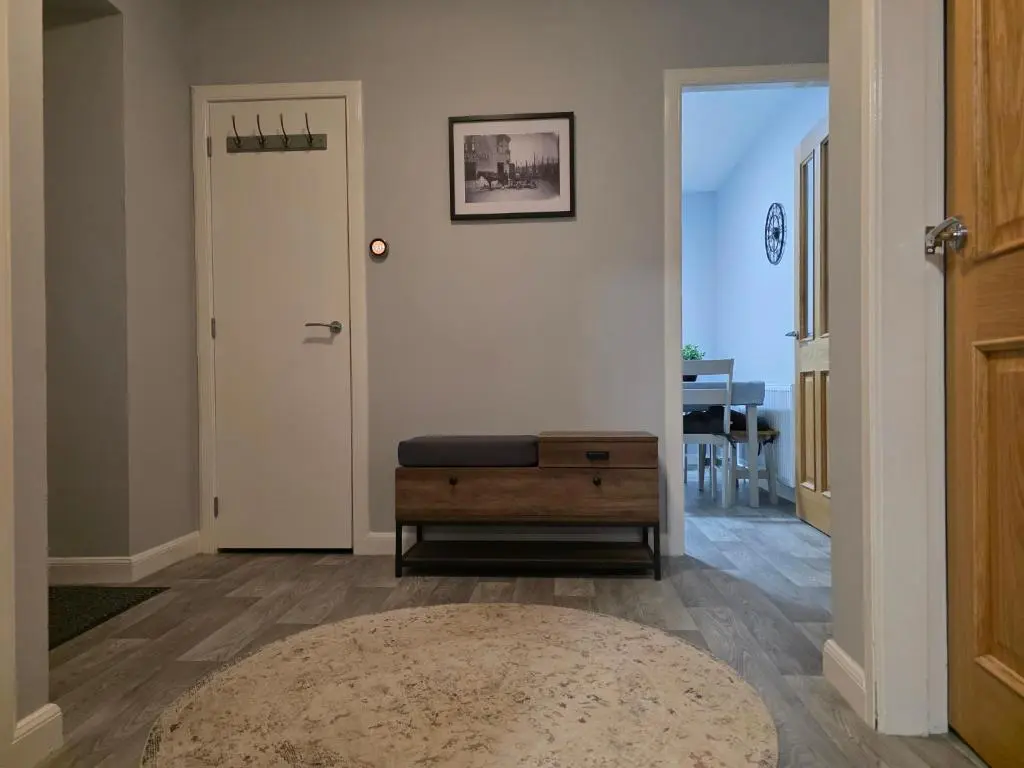 a hallway with a door and a stool and a rug at 14 Harbour View in Wick