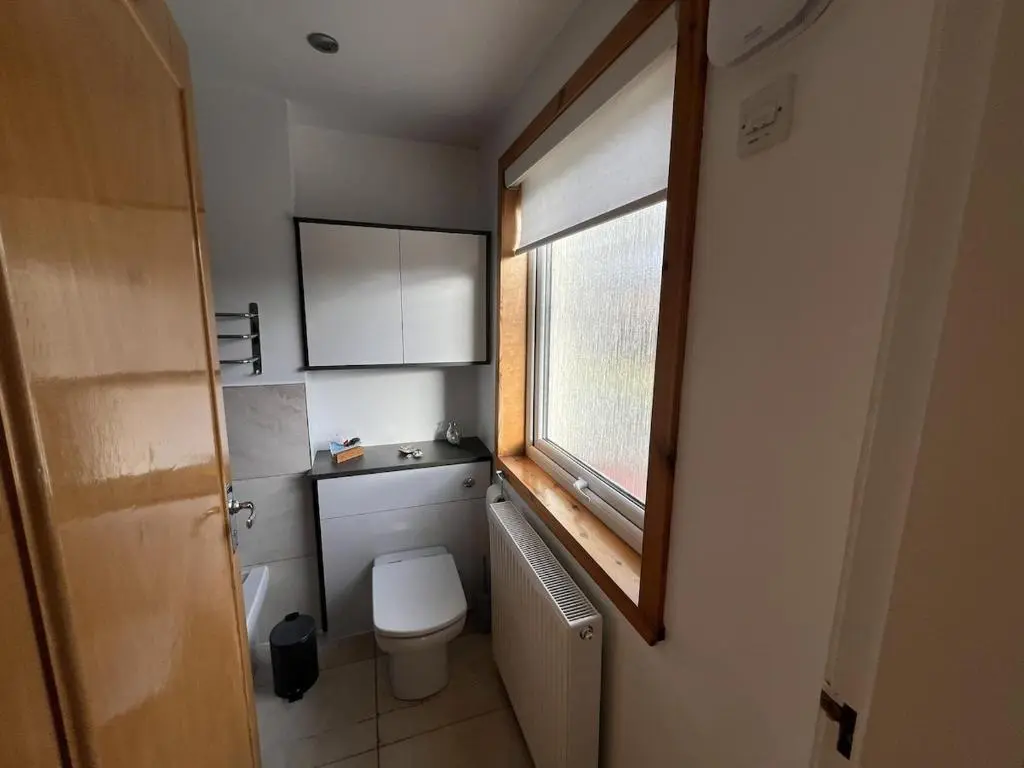 a small bathroom with a toilet and a window at Cluny Corner in Inverness