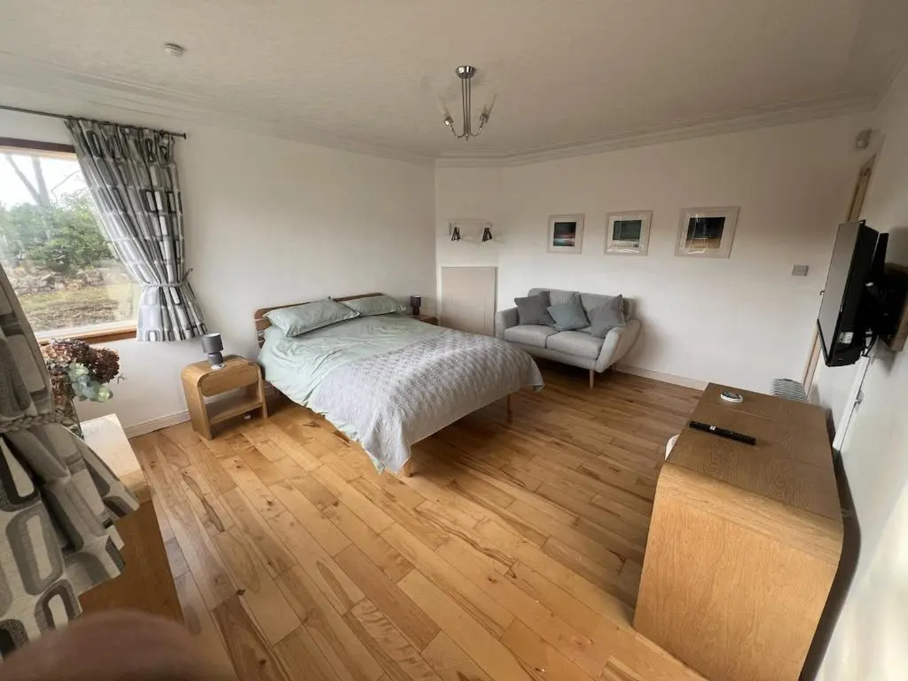 a bedroom with a bed and a couch at Cluny Corner in Inverness