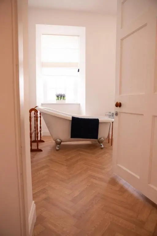 a bath tub sitting in a room with a window at Calder House, Fochabers in Fochabers