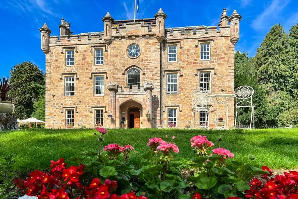 an old brick building with a clock on it at Averon Castle in Alness