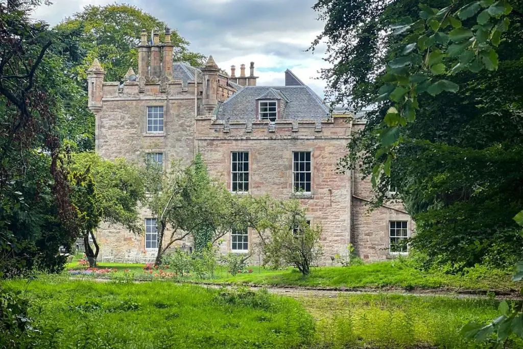 an old stone house with a roof on a field at Averon Castle in Alness