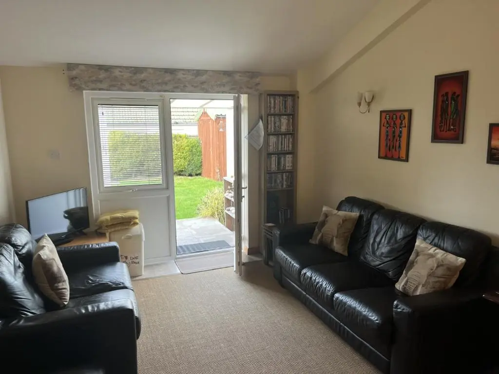 a living room with black leather couches and a sliding glass door at Hopeman Cottage in Hopeman