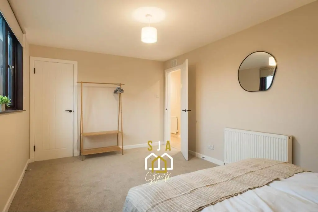 a bedroom with a bed and a mirror on the wall at Fraserburgh Stay - SJA Stays - Modern 2 Bed Apartment in Fraserburgh