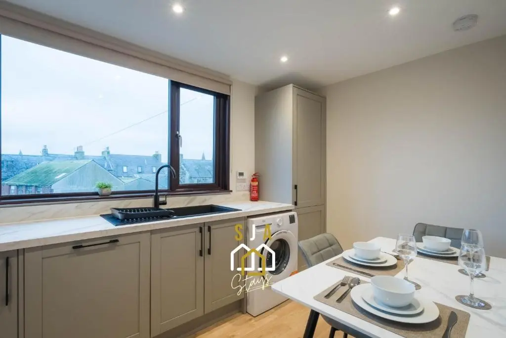 a kitchen with a table and a sink and a window at Fraserburgh Stay - SJA Stays - Modern 2 Bed Apartment in Fraserburgh