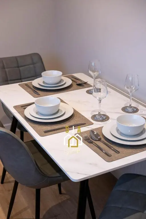 a dining room table with plates and wine glasses at Fraserburgh Stay - SJA Stays - Modern 2 Bed Apartment in Fraserburgh