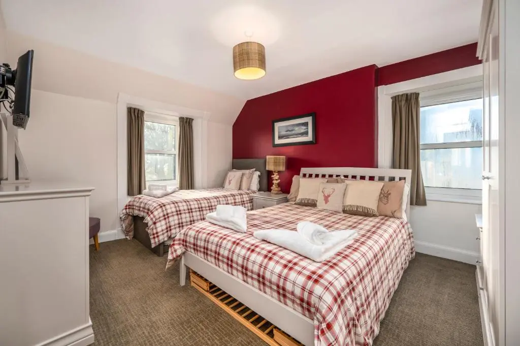 two beds in a room with red walls at Burnside, Dornoch in Dornoch