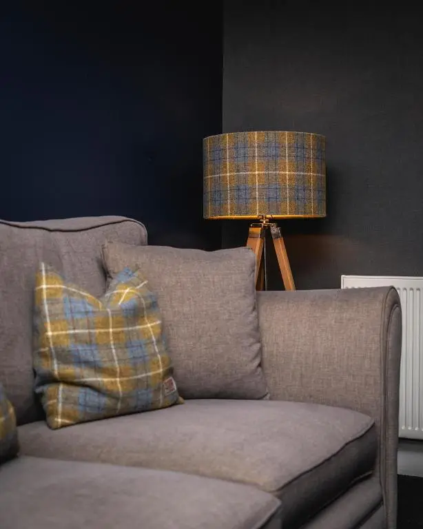 a couch with a plaid pillow and a lamp at Burnside, Dornoch in Dornoch
