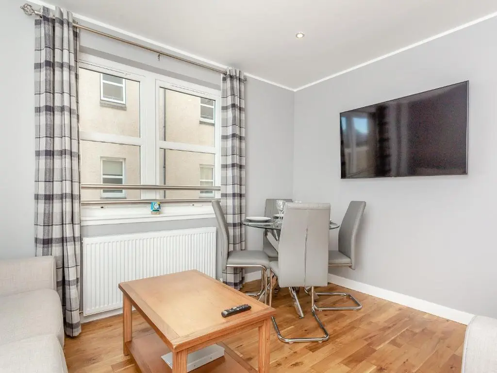 a living room with a table and a tv at Inverness Highland Apartment in Inverness