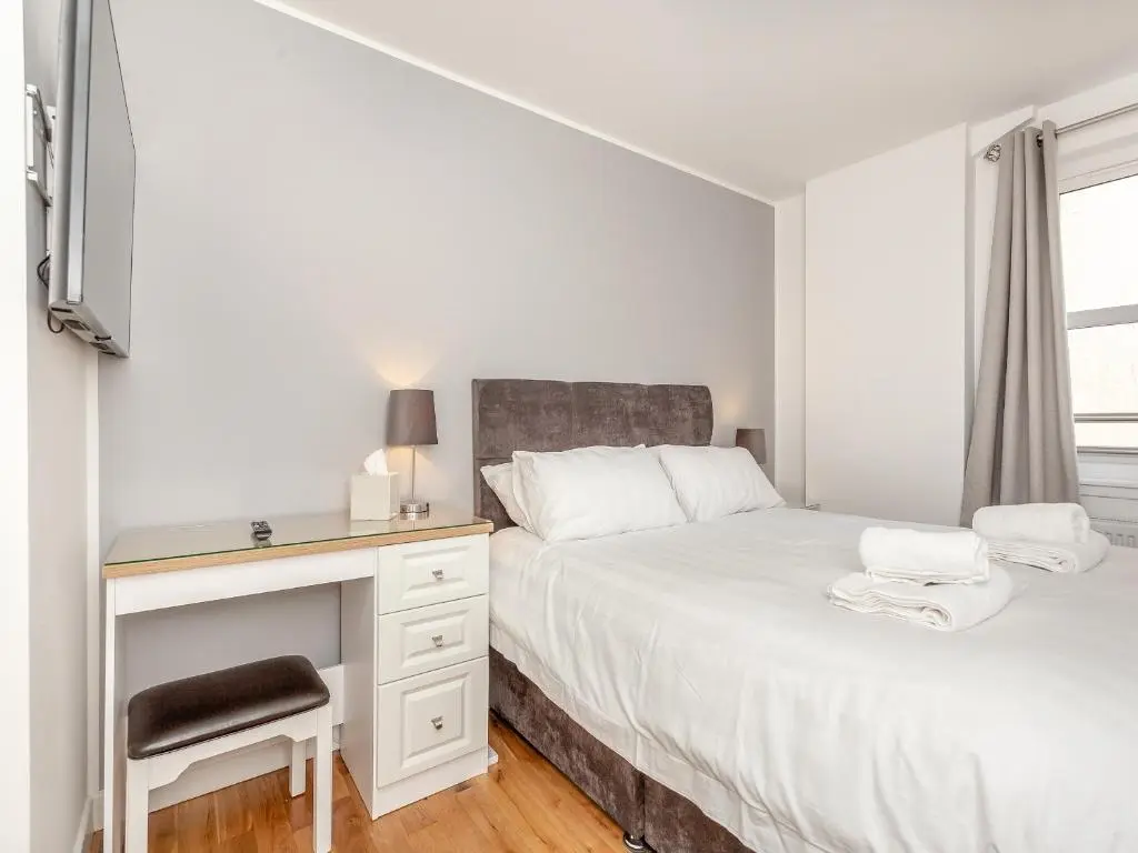 a white bedroom with a desk and a bed at Inverness Highland Apartment in Inverness