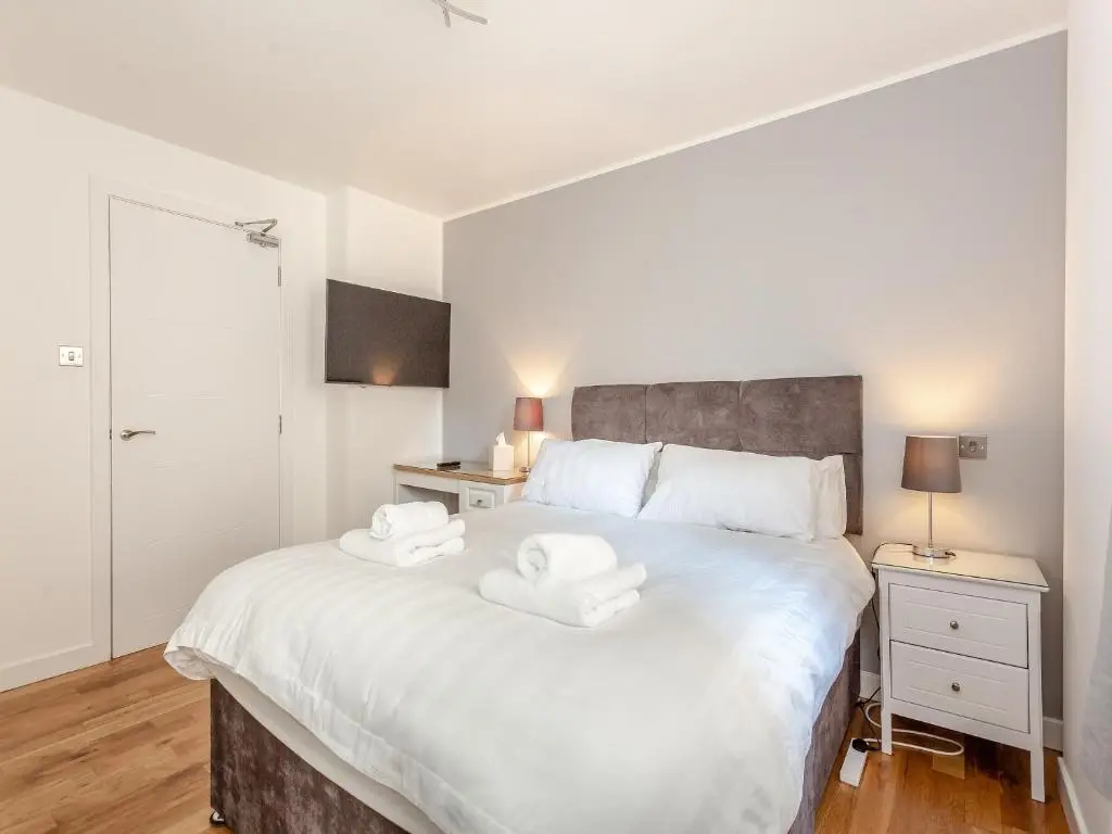 a bedroom with a large white bed with two towels on it at Inverness Highland Apartment in Inverness