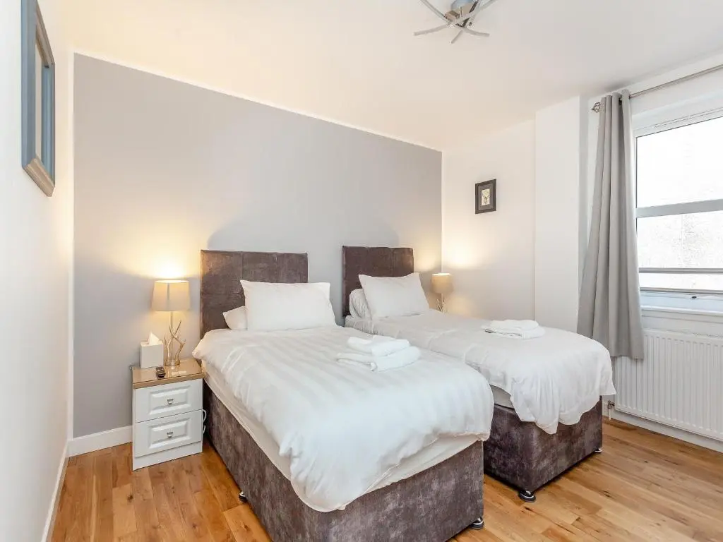two twin beds in a bedroom with a window at Inverness Highland Apartment in Inverness