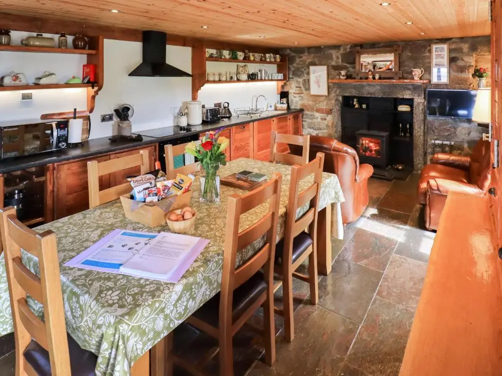 a kitchen with a table and chairs and a stove at Kestrel Cottage in Rogart