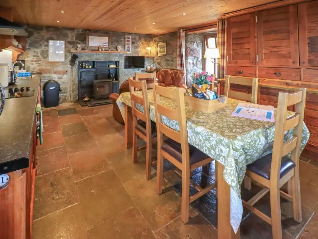 a kitchen and dining room with a table and chairs at Kestrel Cottage in Rogart