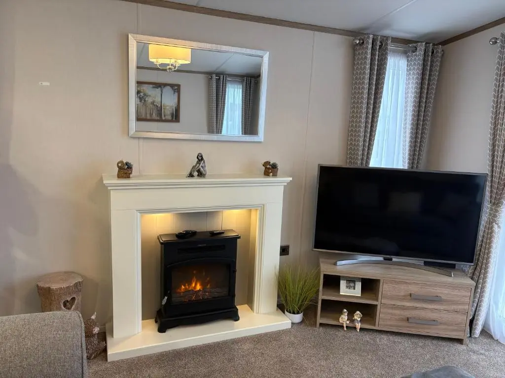 a living room with a fireplace and a flat screen tv at Sunset villa in Lossiemouth