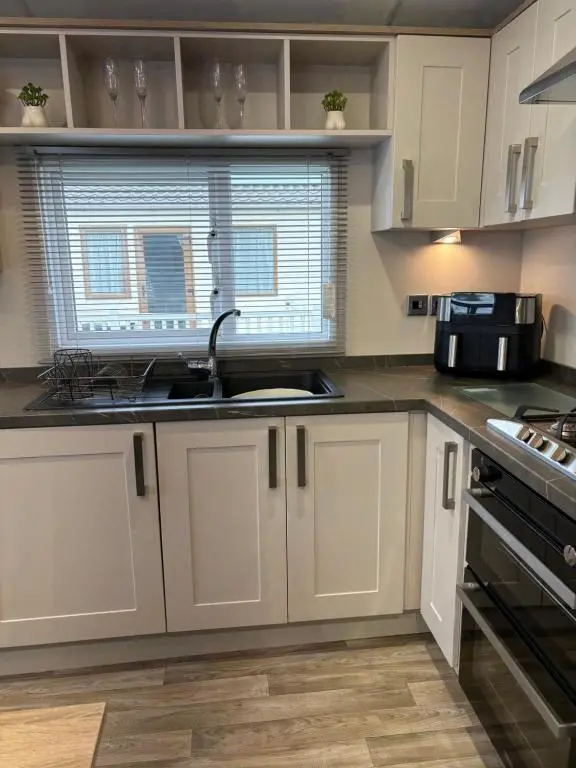 a kitchen with white cabinets and a sink and a window at Sunset villa in Lossiemouth