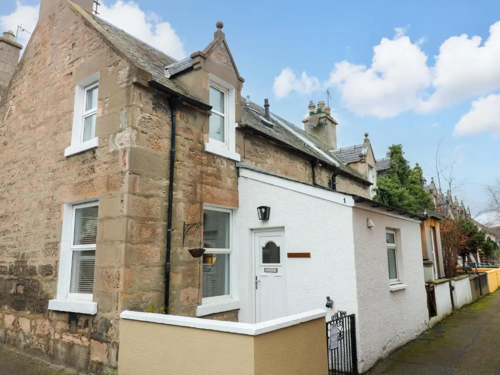 an old brick house with a white door at Rose Cottage in Nairn