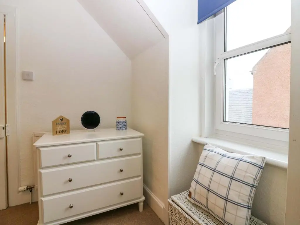a bedroom with a dresser and a window at Rose Cottage in Nairn