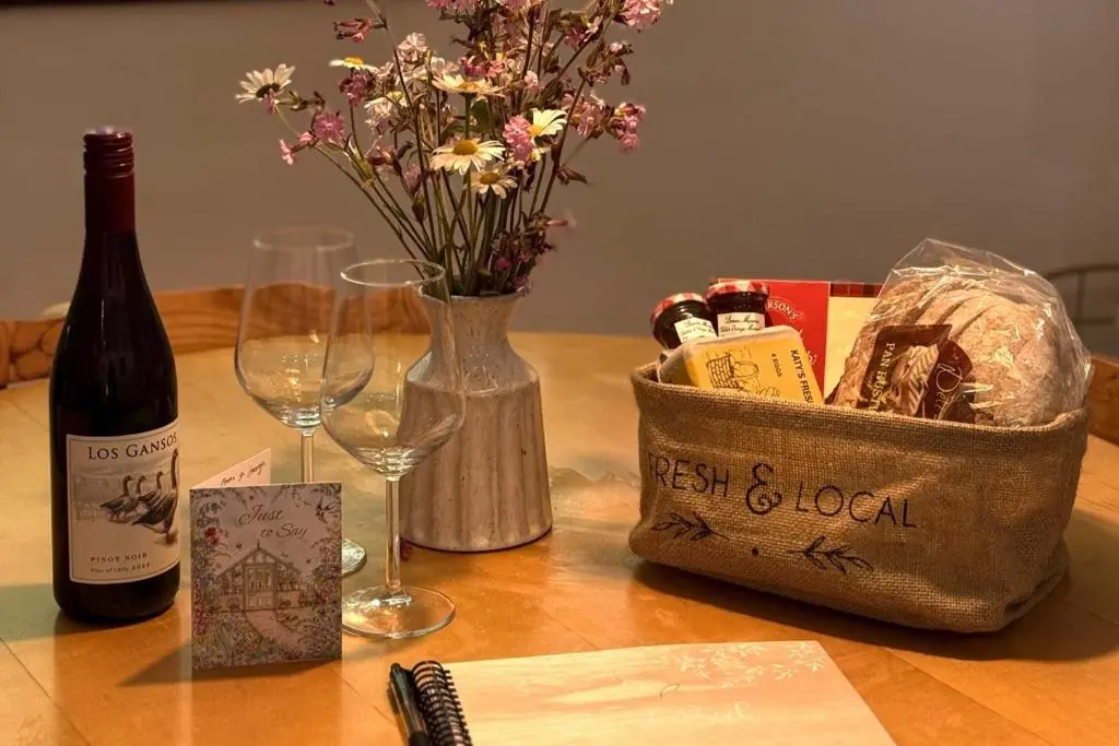 a table with a bottle of wine and a basket of flowers at Pets - Garden - Parking - Sleeps 2 - Hiking in Banchory