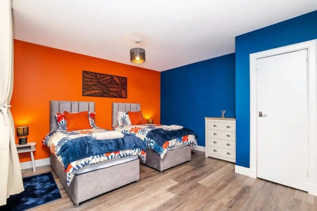 two beds in a room with orange and blue walls at Aberdeen Airport Cozy Apartment - 3 Beds - Sleeps 5 with Free Parking and Fast Wi-Fi in Aberdeen