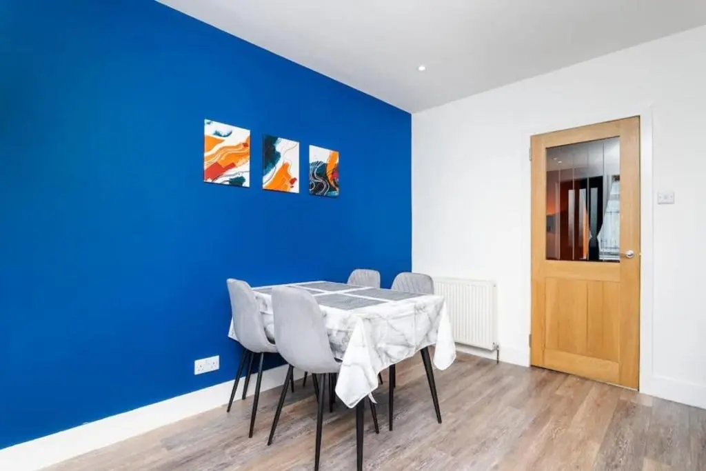 a dining room with a blue wall and a table and chairs at Aberdeen Airport Cozy Apartment - 3 Beds - Sleeps 5 with Free Parking and Fast Wi-Fi in Aberdeen