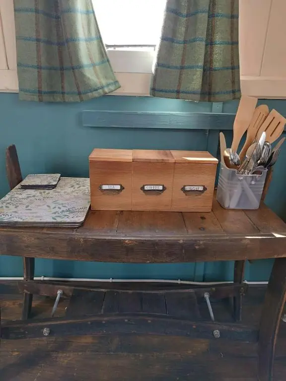 a wooden table with a drawer and utensils on it at The Rumster Hut in Lybster