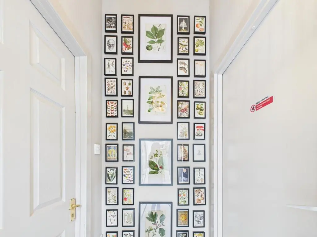 a wall of framed photos on a wall in a hallway at Glenshee Suite, Beechtree Cottage in Kirkmichael