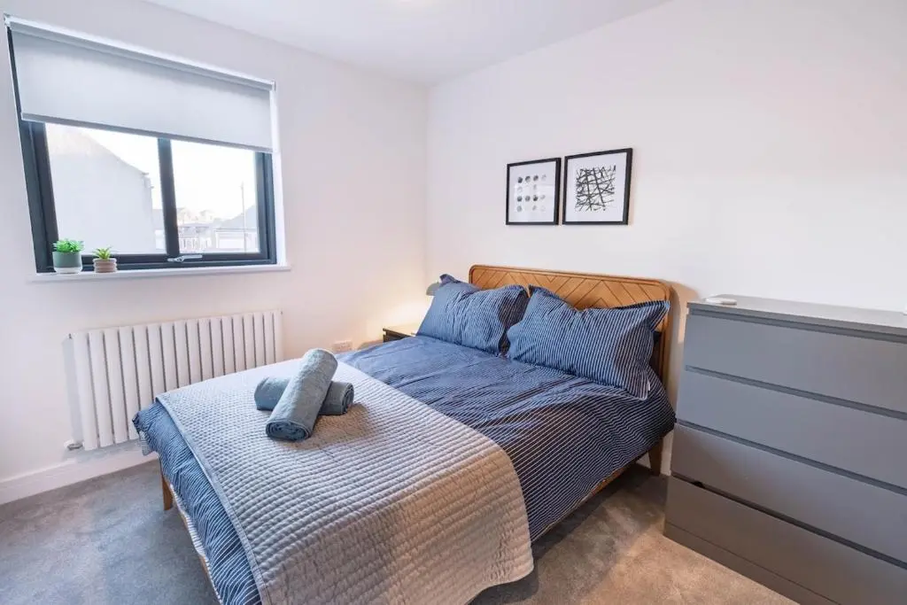 a bedroom with a bed and a dresser at Modern Central Apartment Huntly in Huntly