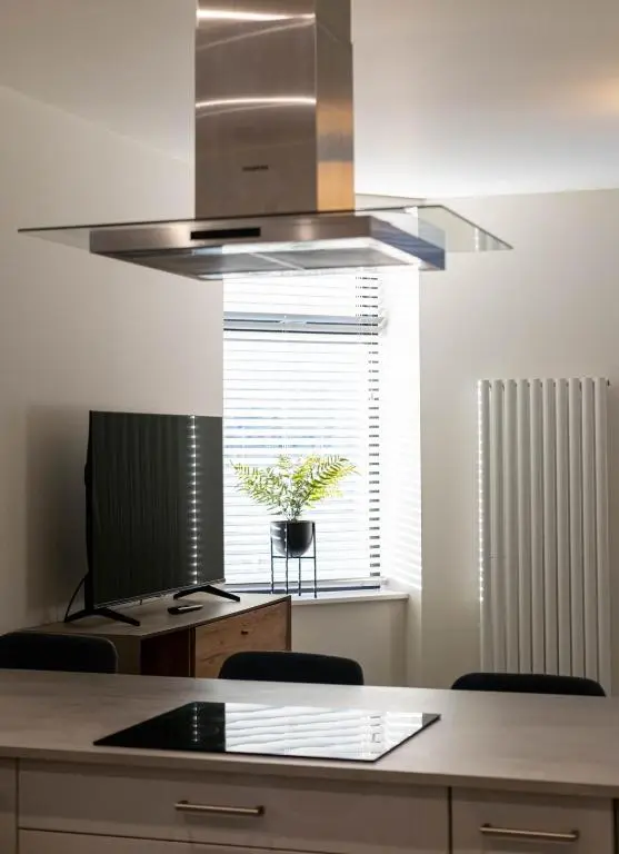 a kitchen with a stainless steel hood over a table at Modern Central Apartment Huntly in Huntly