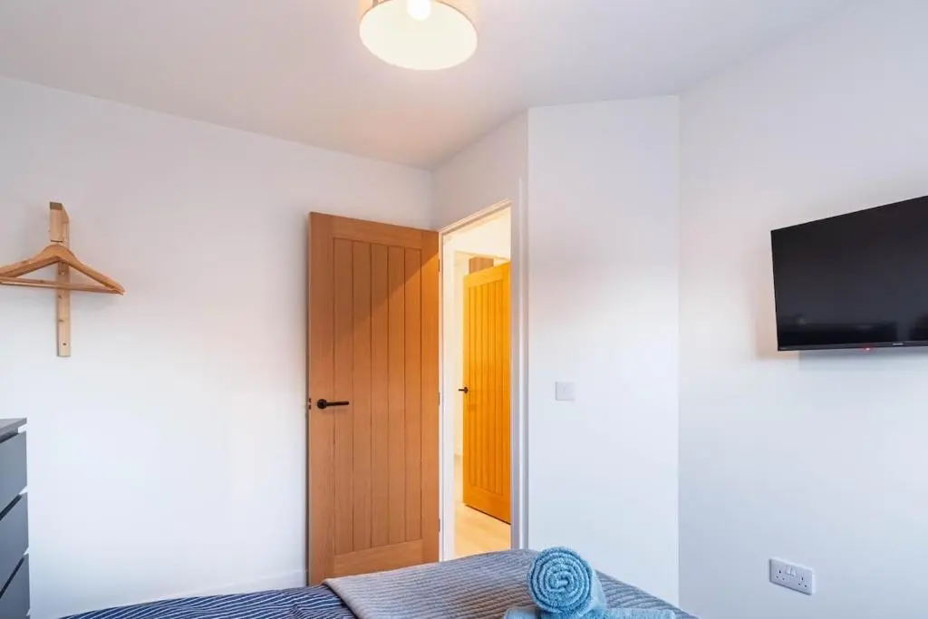 a room with a bed and a television and a door at Modern Central Apartment Huntly in Huntly