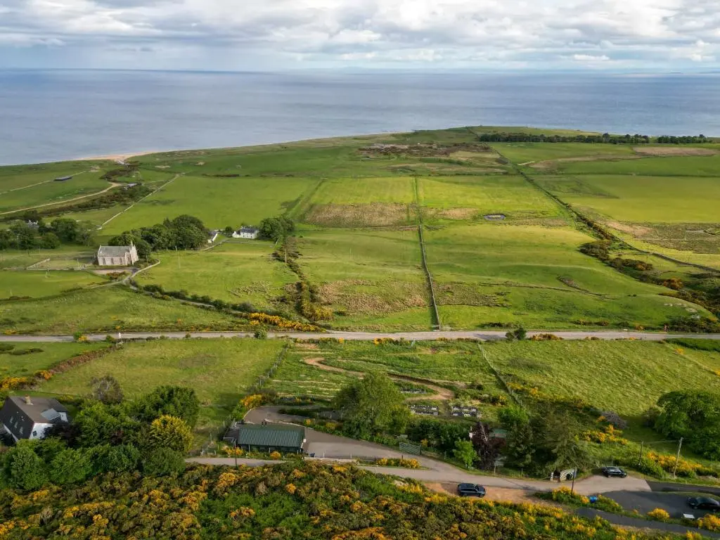 an aerial view of a field with the ocean at Lothmore Lookout - Sunrise in Kilmote