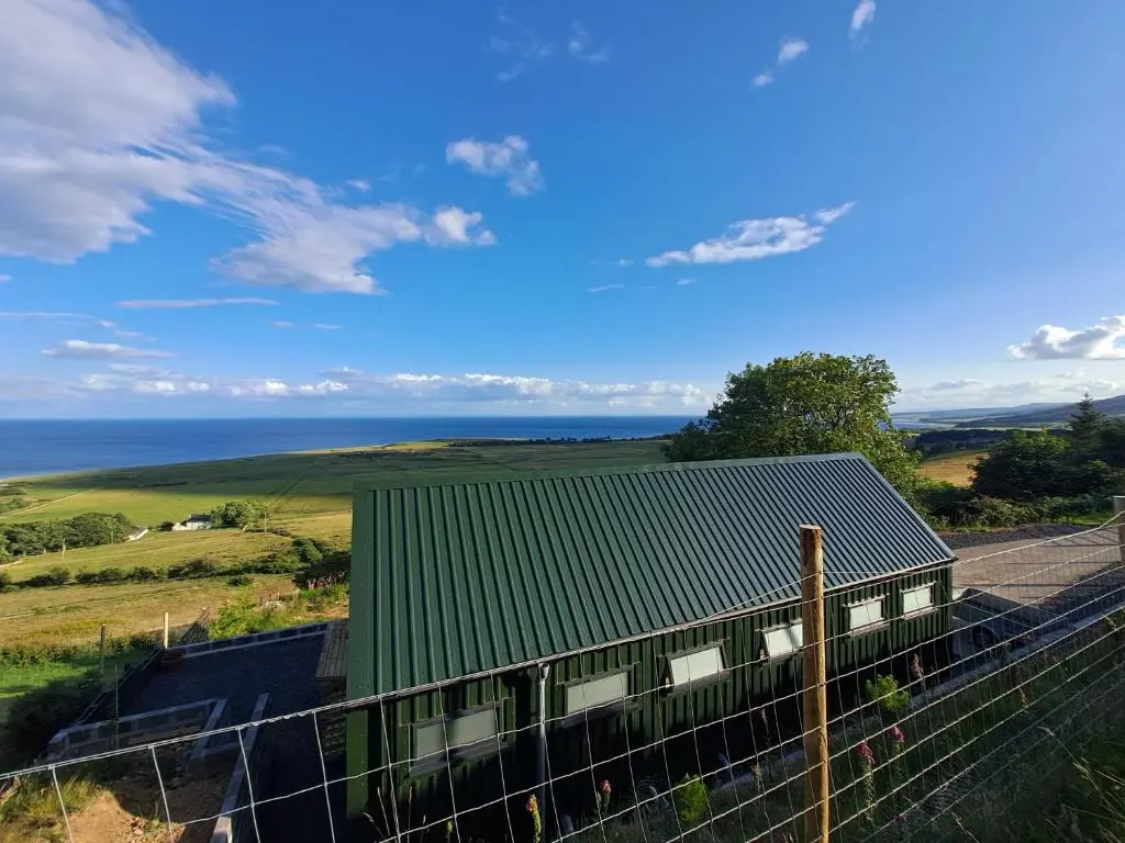 a house with a green roof and a fence at Lothmore Lookout - Sunrise in Kilmote
