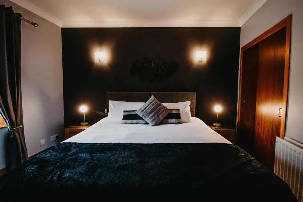 a bedroom with a large bed with two lamps at Seafield Arms Hotel in Whitehills