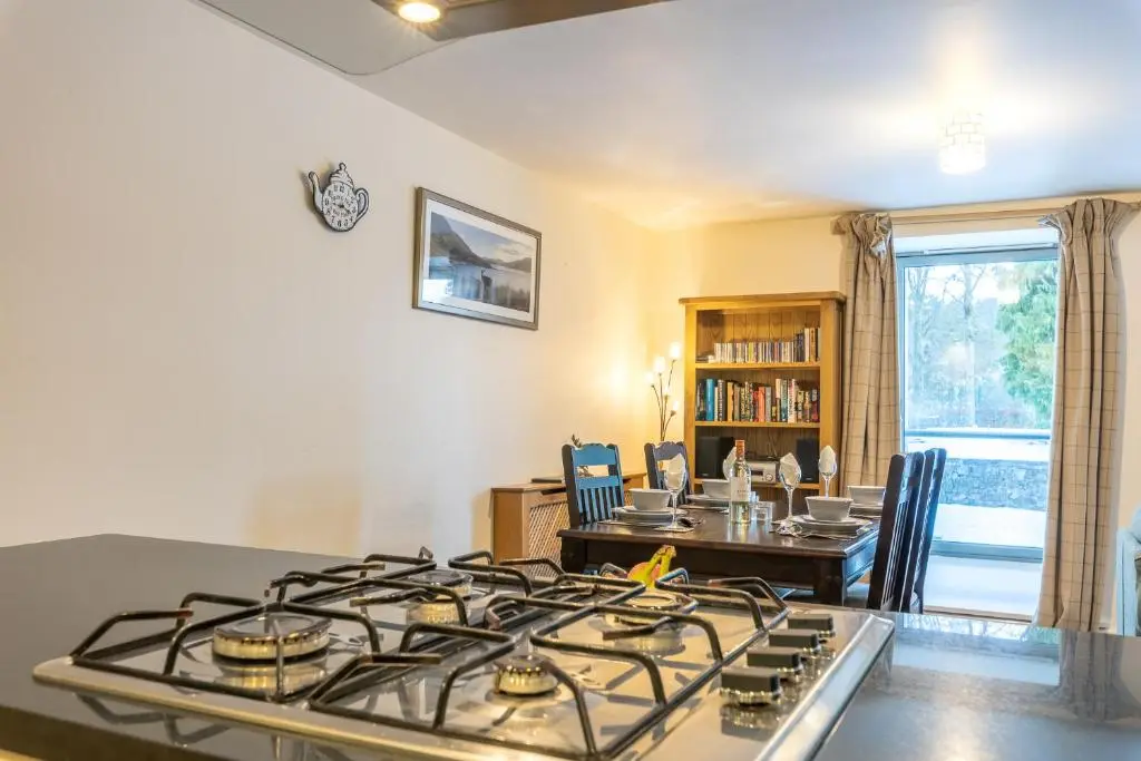 a kitchen with a stove and a dining room at Torr Apartment Raven in Fort Augustus